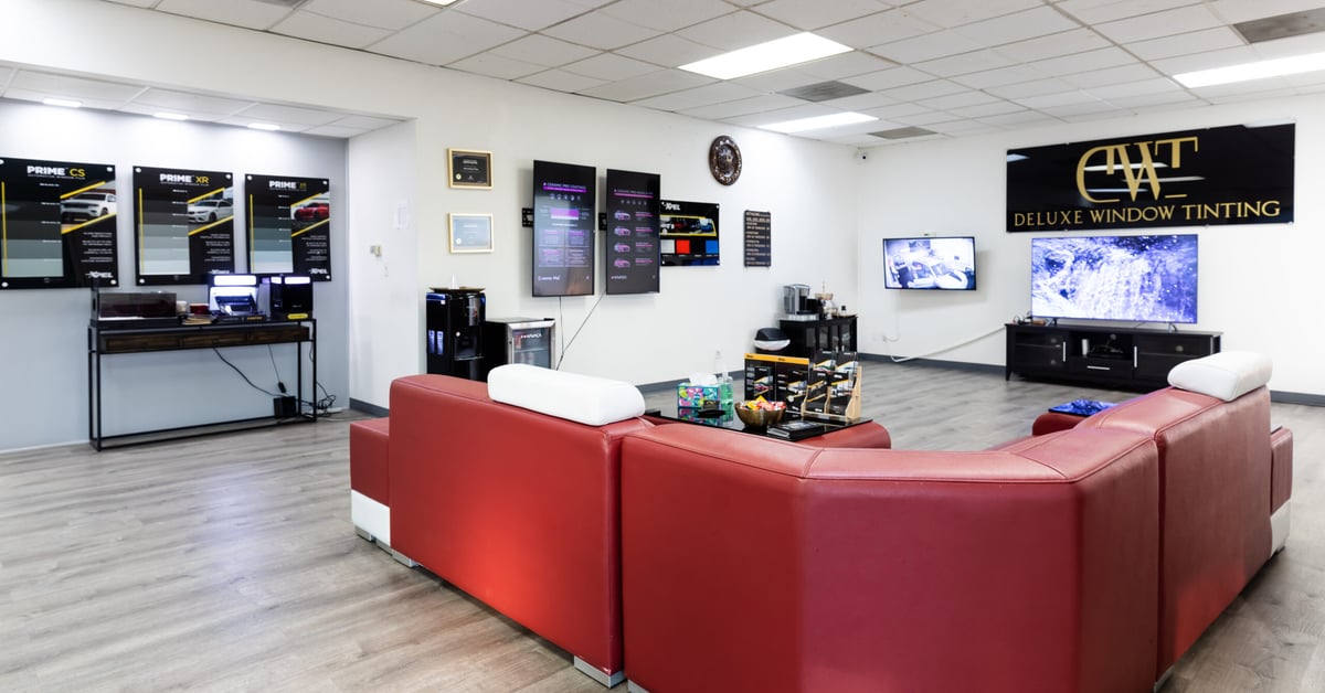 Modern customer waiting room at Deluxe Window Tinting in Gold River, CA with red leather seating and product displays.