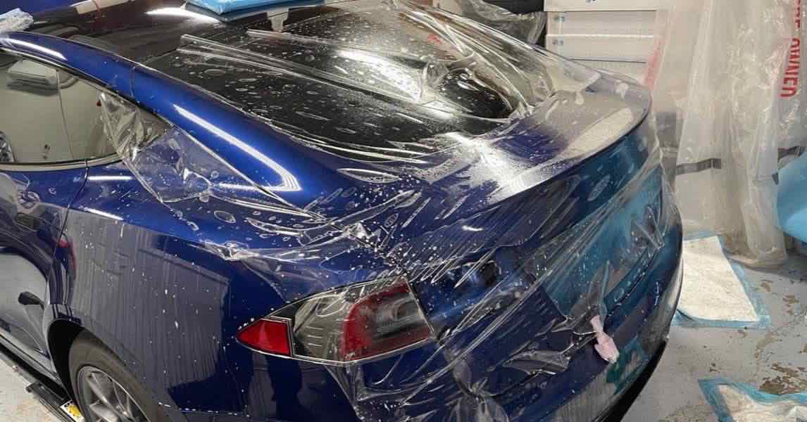 Clear paint protection film being applied to a blue Tesla at a Gold River auto detailing shop.