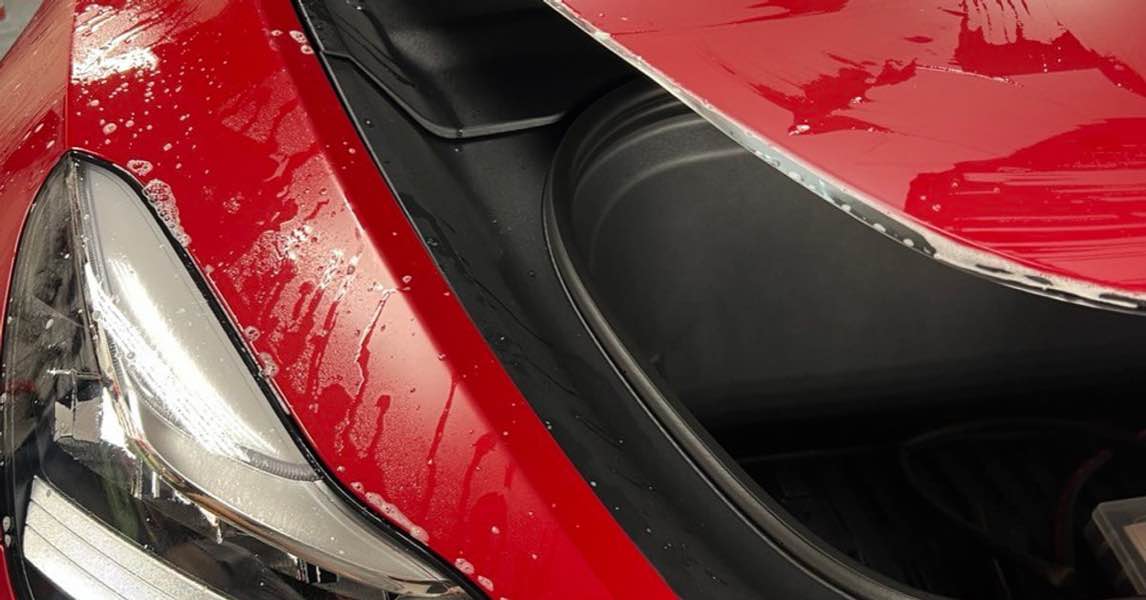 Red Tesla receiving paint protection film installation on the hood and front fender in Gold River.
